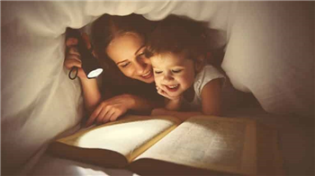 two children with a torch reading under covers
