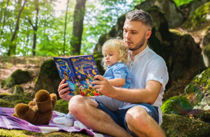image of a baby girl reading a book with parent or carer in the outdoors